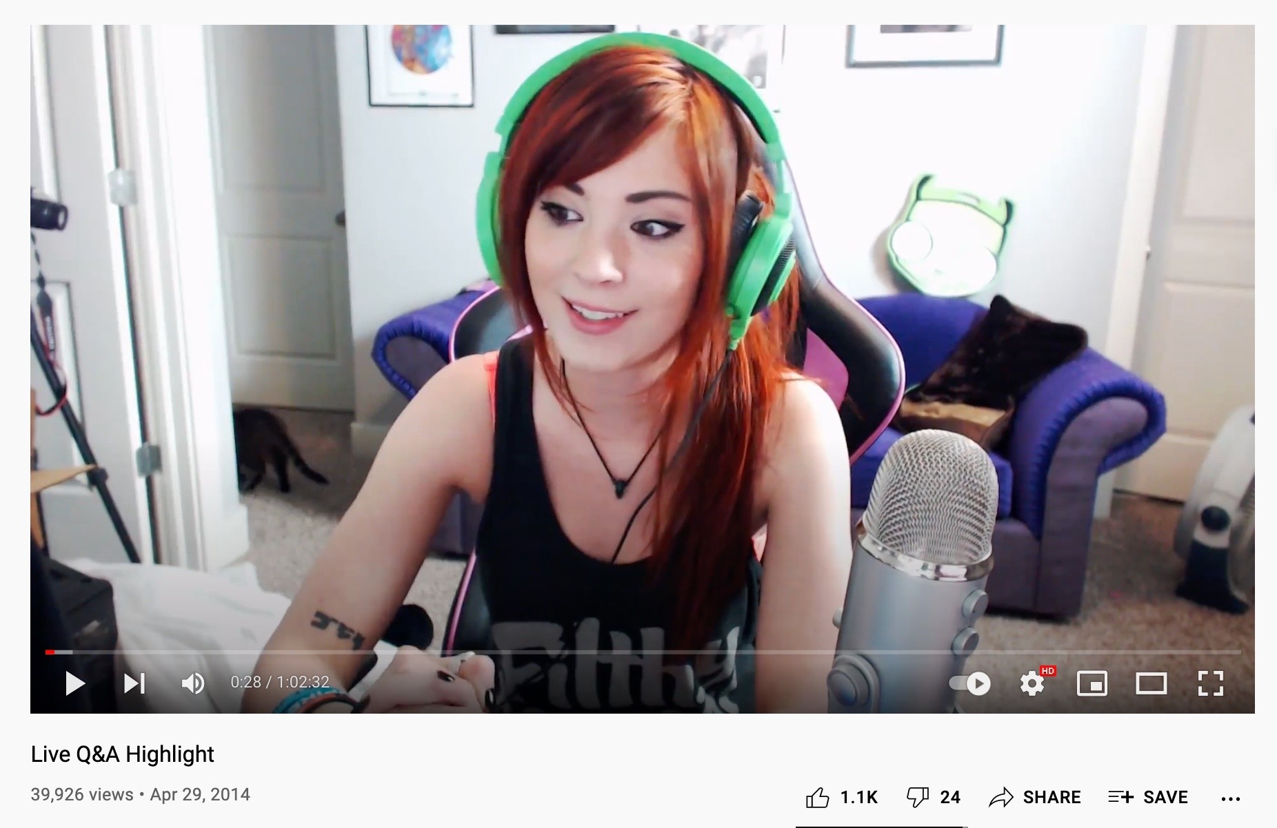 A woman with red hair is wearing headphones on a live stream
